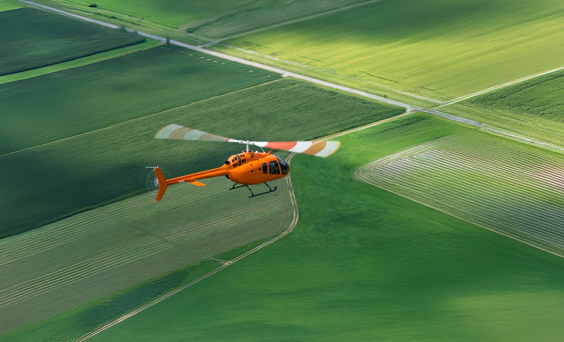 Escuela de vuelo Next Bell 505 volando sobre campo verde