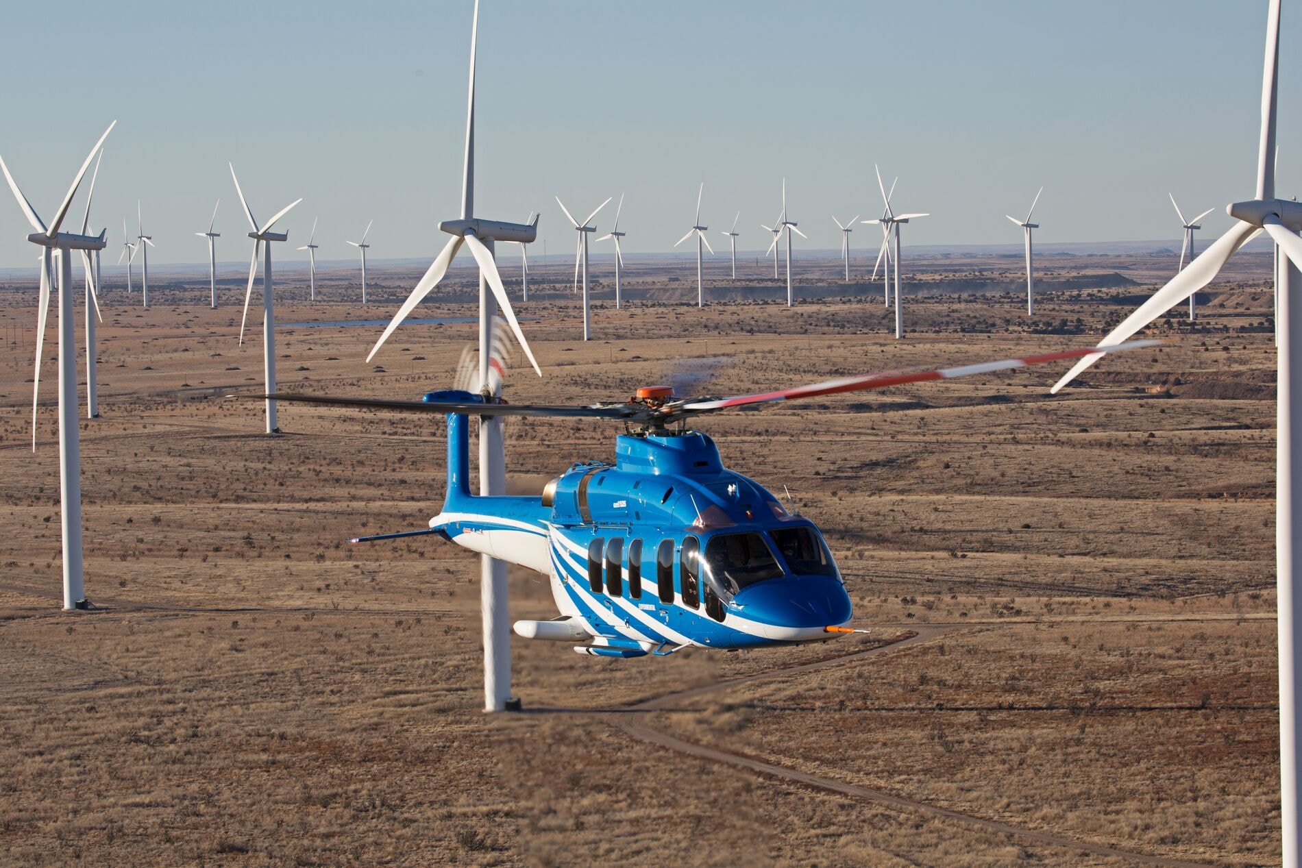Bell 525 volando sobre un campo eólico en el desierto